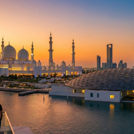 Un homme contemple la Grande Mosquée Sheikh Zayed, le Louvre Abu Dhabi et la ville au coucher de soleil flamboyant.