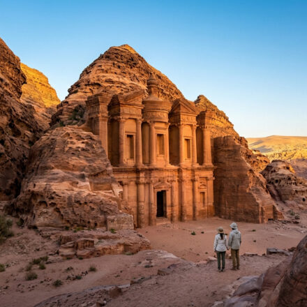 Le Monastère (Ad Deir) de Pétra, Jordanie, majestueuse structure nabatéenne sculptée dans la roche. Deux personnes l'admirent au crépuscule.