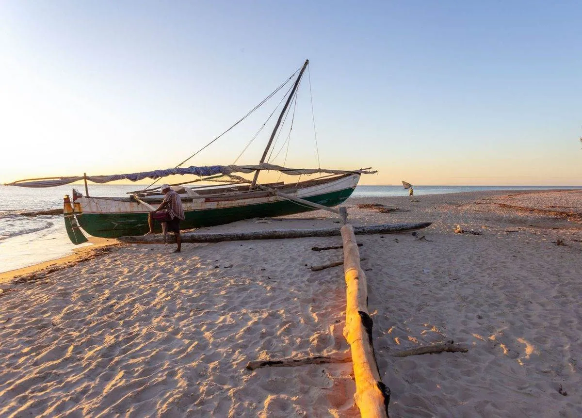 Pirogue à voile sur une plage de Madagascar au coucher du soleil